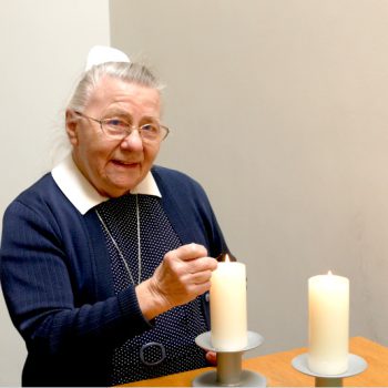 Diakonisse entzuendet eine Kerze auf dem Altar